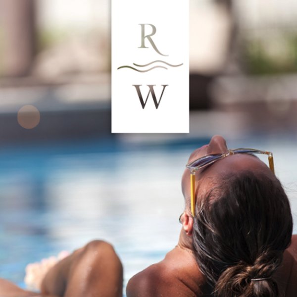 A woman relaxing at the edge of a pool below the Riverwalk RW logo